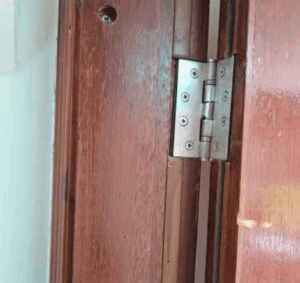 Fire door hinge showing missing intumescent seal and damage in a healthcare facility